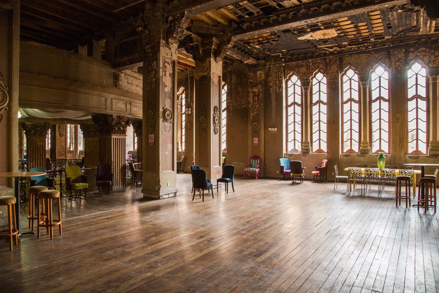 Salón con piso de madera y ventanales en arco