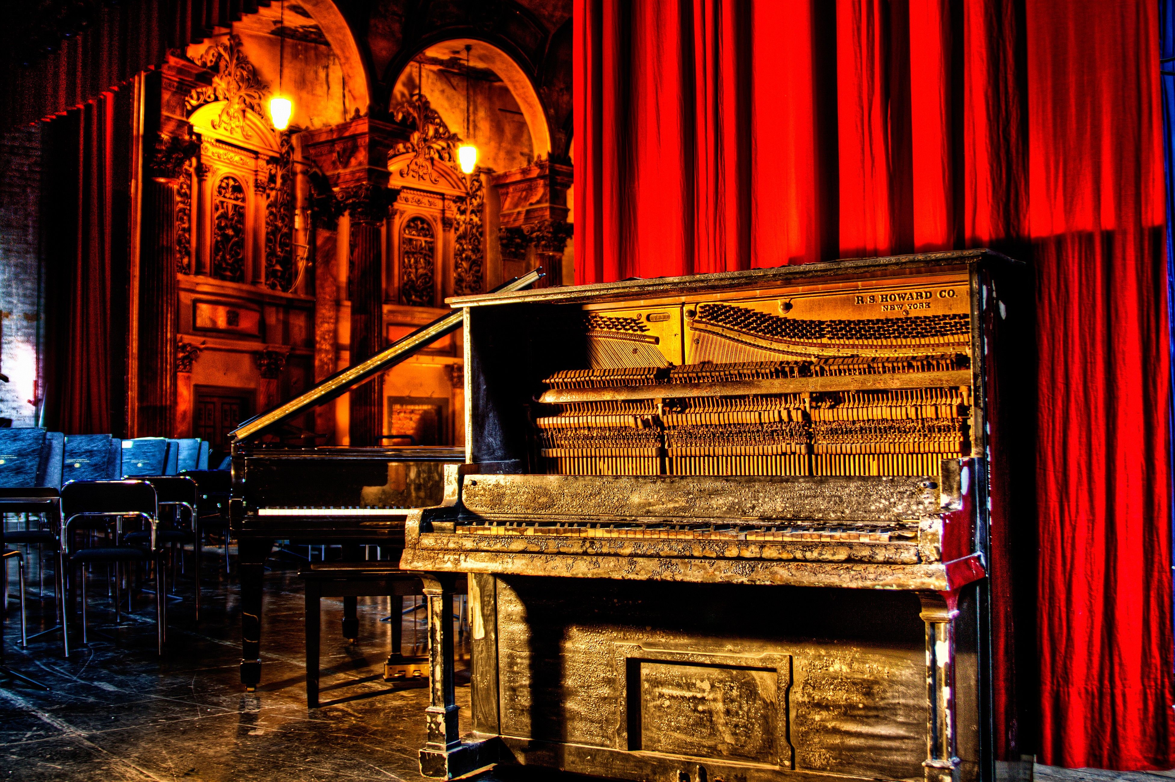 Piano antiguo junto al telón rojo