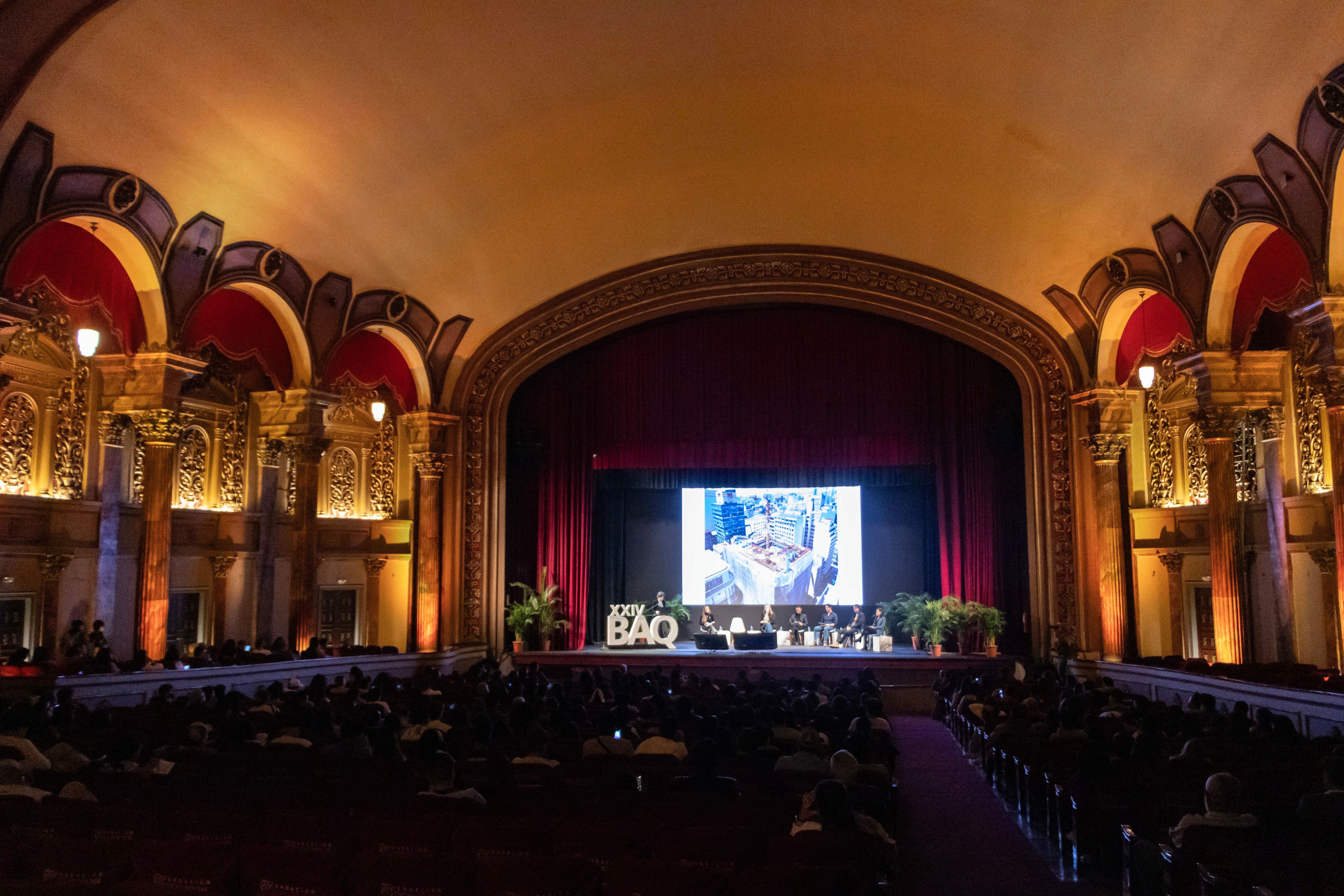 Sala durante un evento con pantalla sobre el escenario